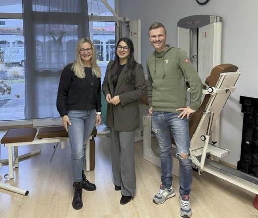 Auf dem Foto abgebildet sind Markus Neumann, Physiotherapeut und Praxisinhaber, sowie
Tanja Hübner-Neumann, Ergotherapeutin und Praxisinhaberin. In ihrer Mitte steht Mahwish Iftikhar. Sie stehen in einem Praxisraum mit Physiotherapiegeräten.